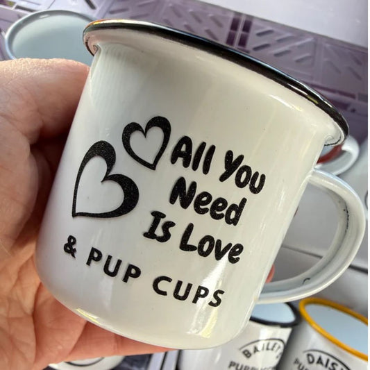 White mug with 'All you need is love & pup cups' text held by a hand.