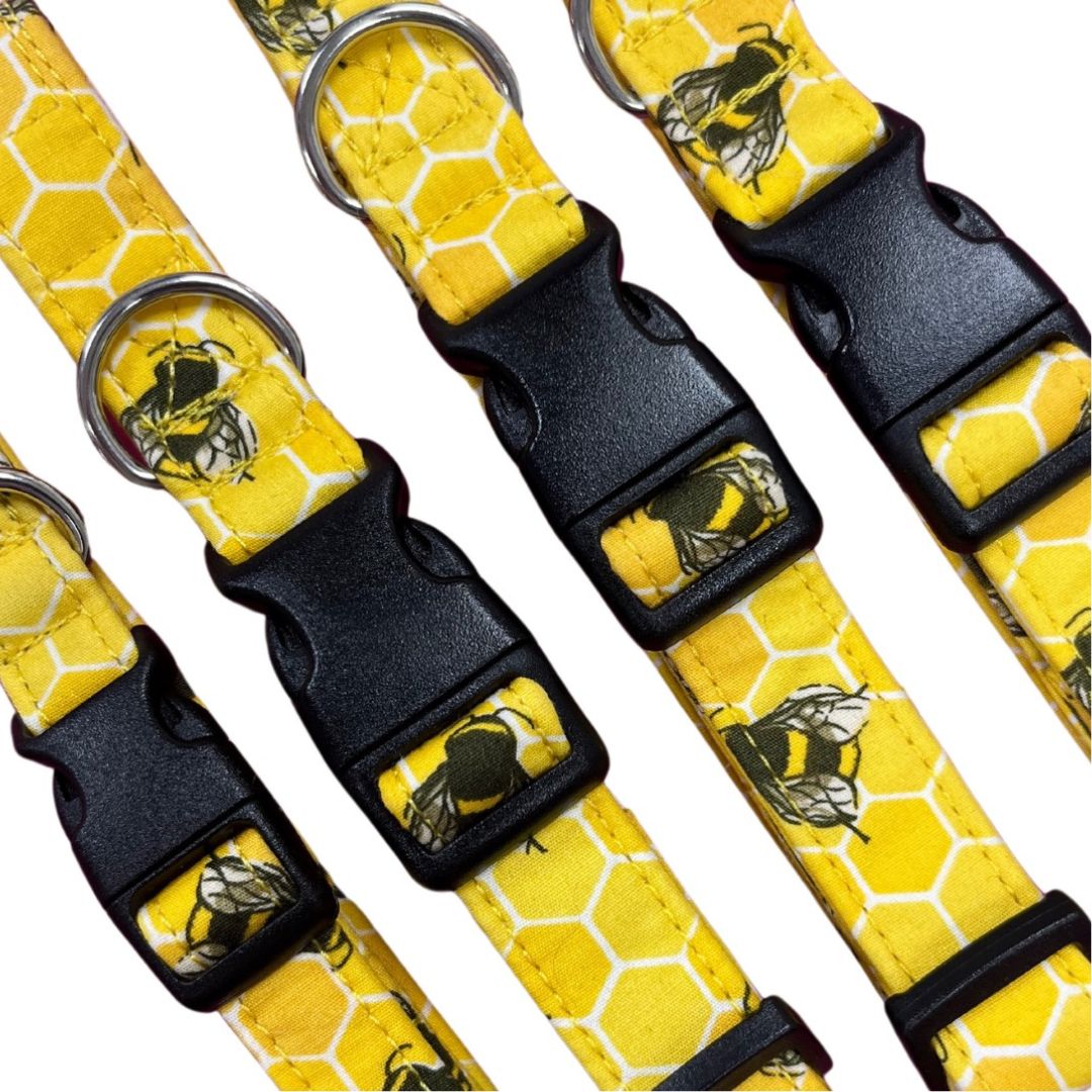 A collection of yellow dog collars with a bee hive print and plastic buckles.