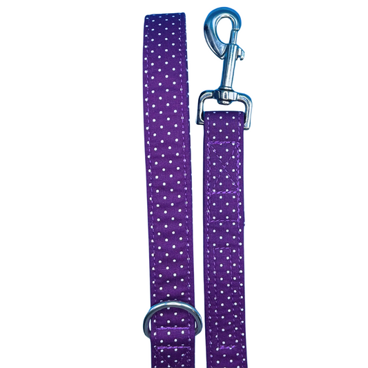 A purple dog lead with white polka dots and silver metal hardware, including a swivel clip and D ring.