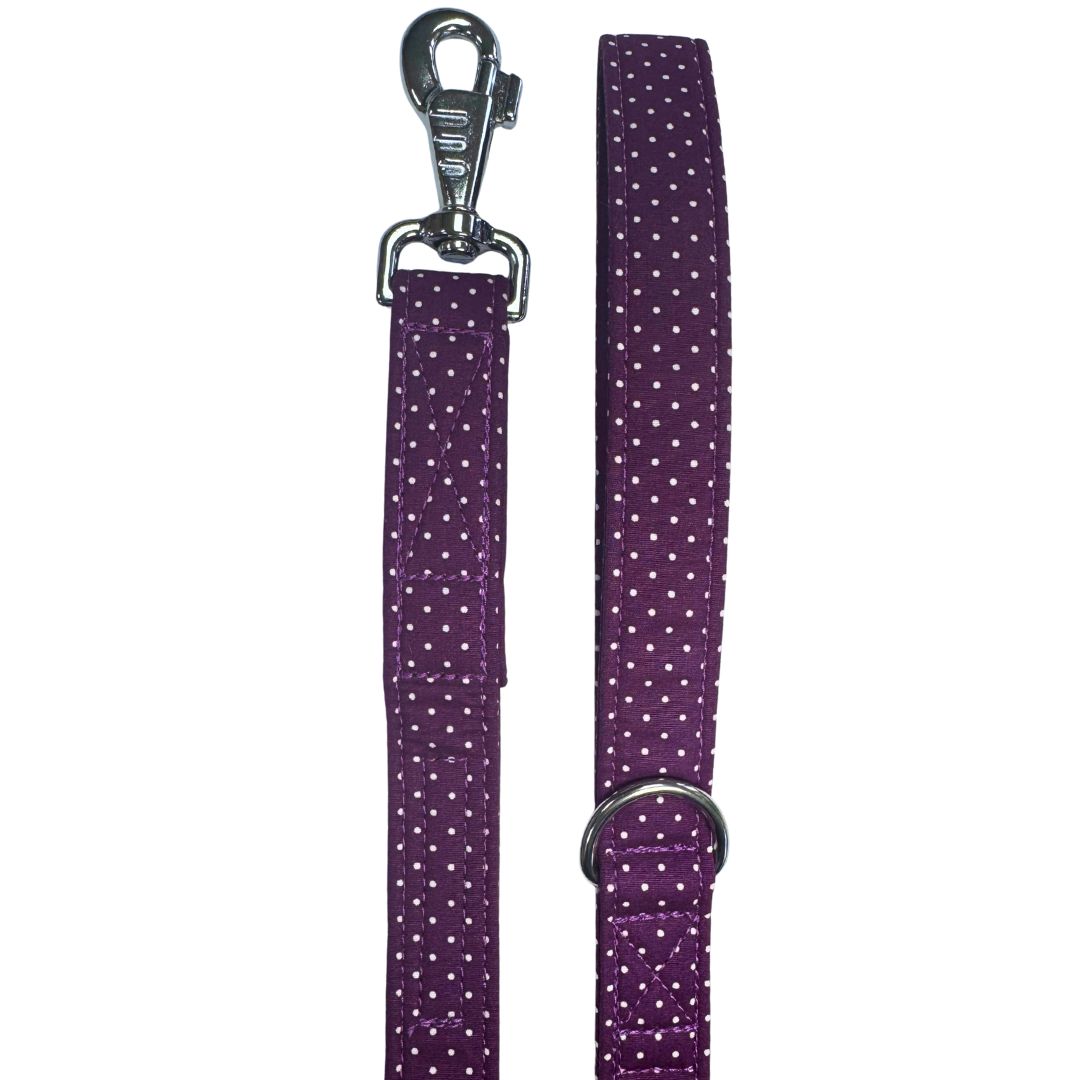 A purple dog lead with white polka dots and silver metal hardware, including a swivel clip and D ring.
