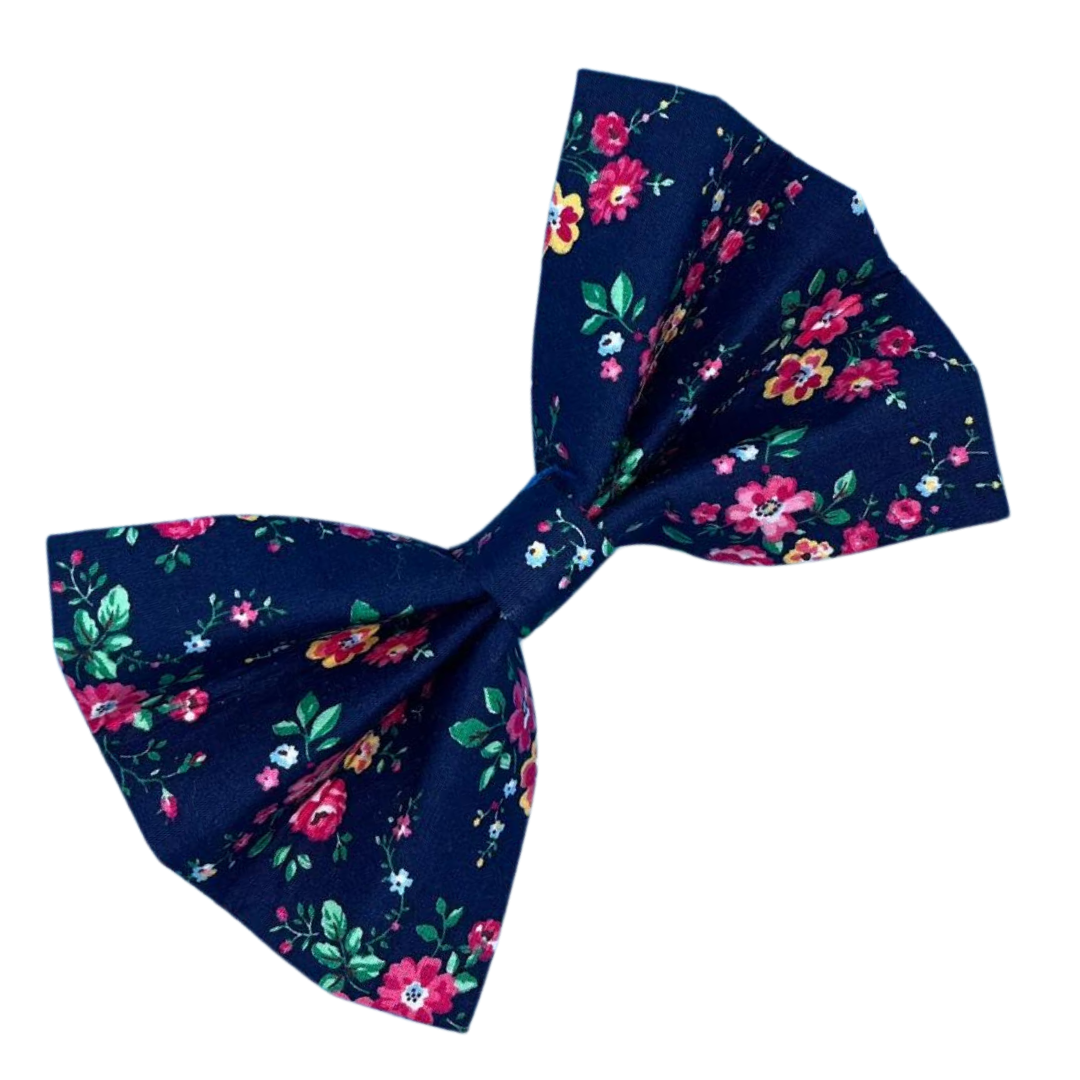 A navy blue dog bow tie with a floral pattern, featuring pink and green flowers.