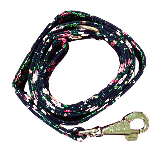 A coiled dog lead with a navy base covered in a floral pattern, featuring silver metal hardware.