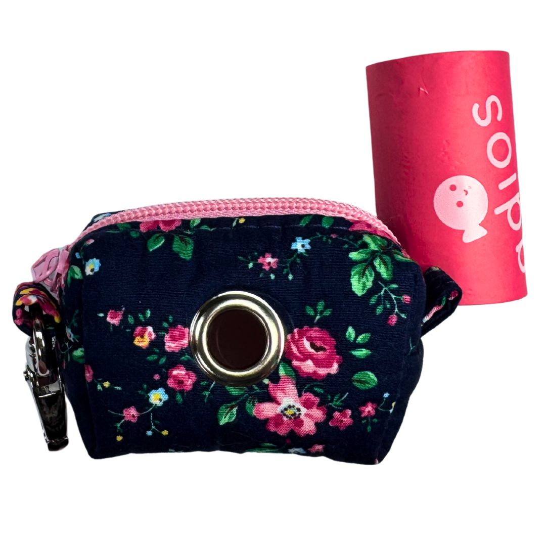 Floral-patterned poo bag holder with pink zip and keychain, with a roll of adios poo bags.
