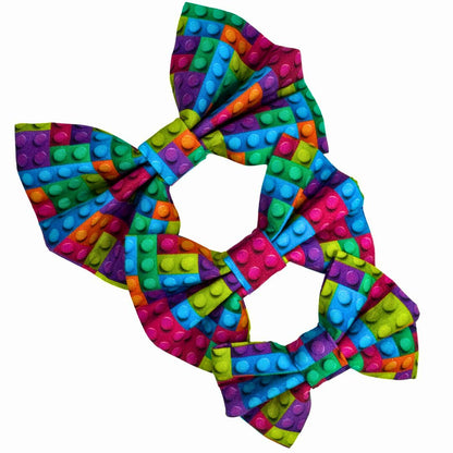 Three colourful cotton dog bows in small, medium and large with a building block pattern.