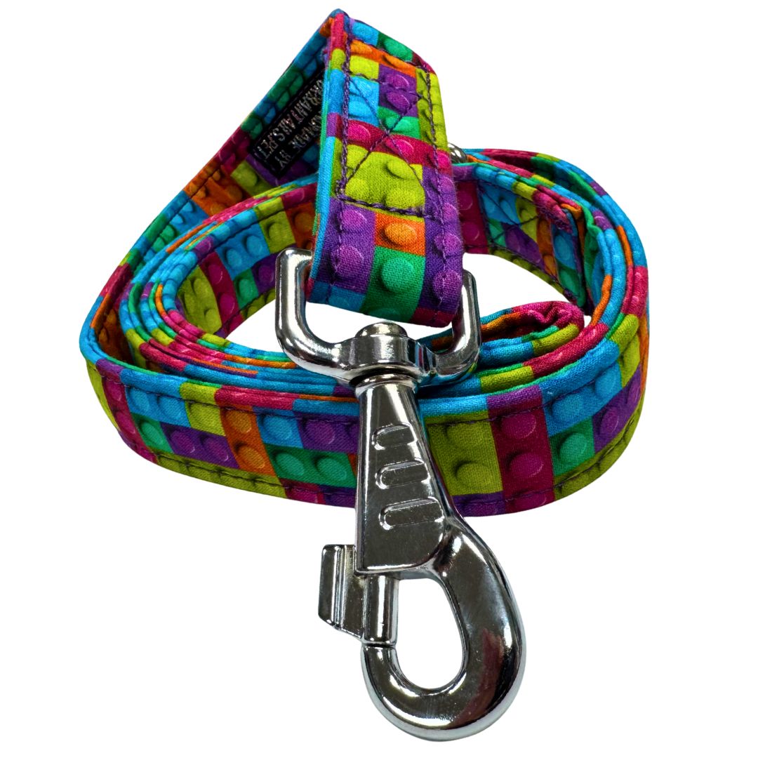 A close up view of the building block dog leash which is bright and playful with a metal swivel clip.