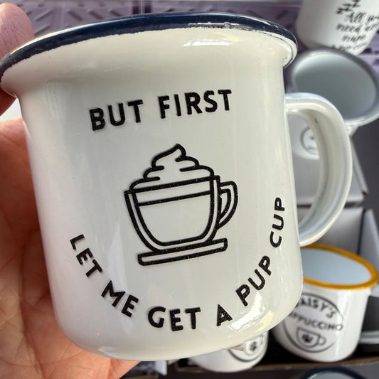 White mug with black text and a cup icon, held in a hand.