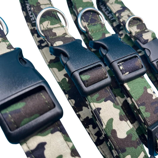 A close up of camo print dog collars with plastic buckles and metal D rings, arranged side by side.