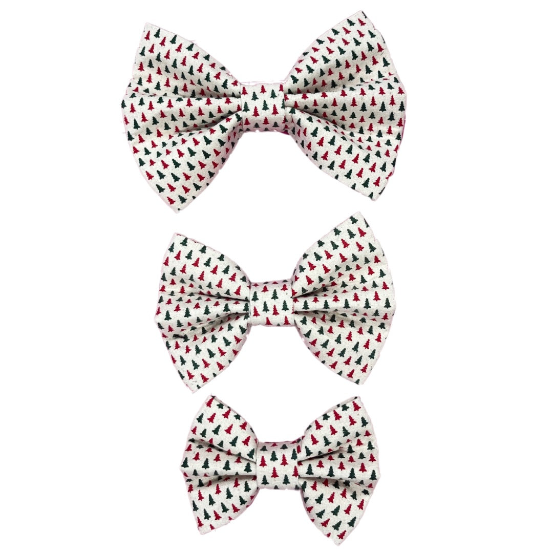 Three handmade dog bow ties in small, medium and large with red and green Christmas trees on a white background.