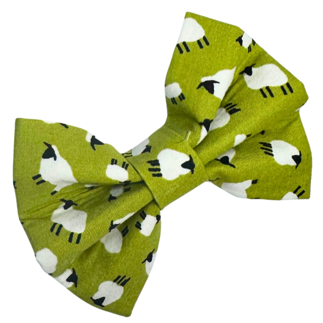Green dog bow with a sheep pattern that has elastic that slides in the collar