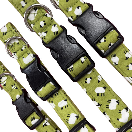 A close up of a collection of green dog collars with a white sheep print, featuring plastic buckles and metal D rings.
