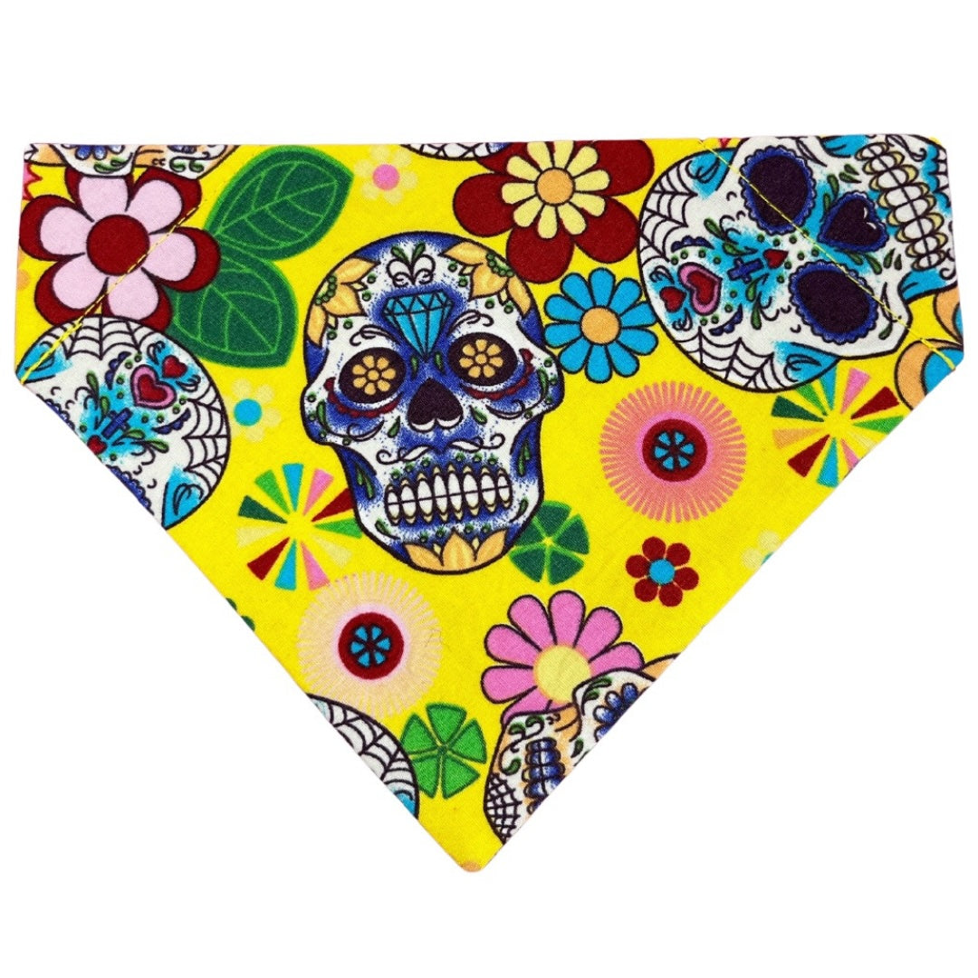 A colourful handmade bandana featuring a Day of the Dead skull design with vibrant flowers and patterns on a yellow background.