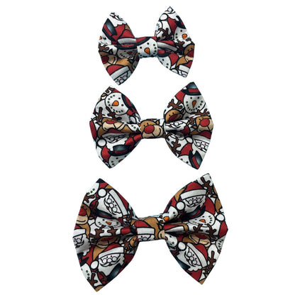 Three festive bow ties in small, medium and large with a Christmas-themed pattern featuring Santa, snowmen and reindeer on a red and white background.