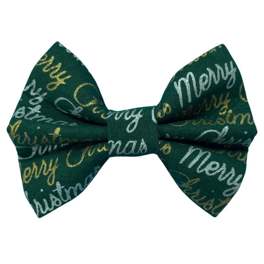 A green bow tie with 'Merry Christmas' text and gold and silver accents.