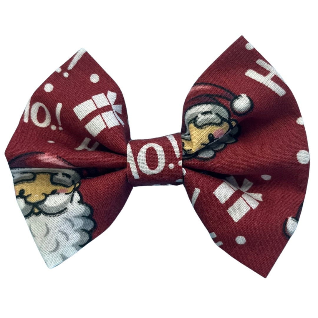 A handmade red bow tie with text 'ho ho ho' and images of Santa Claus and presents