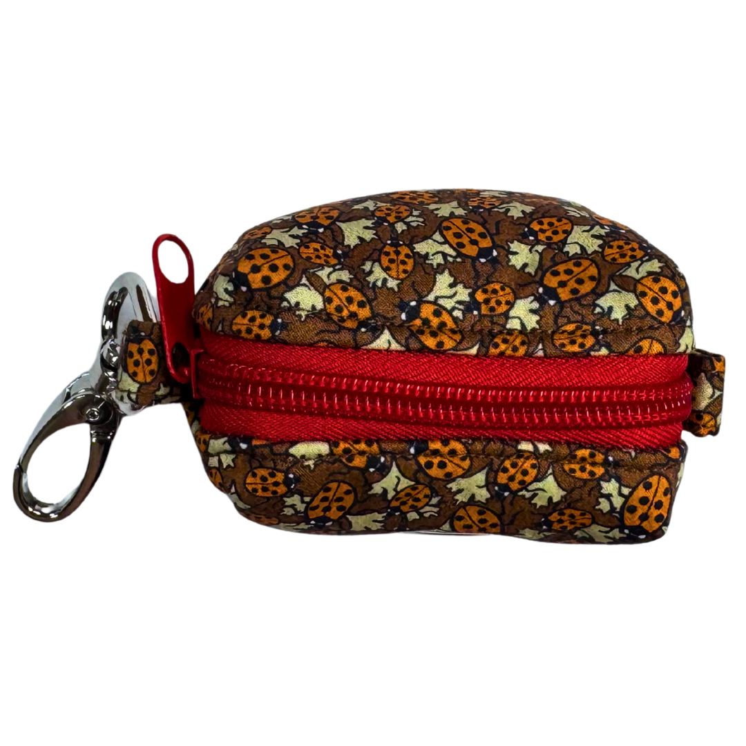 Top view of a poo bag holder with ladybug pattern and red zipper.