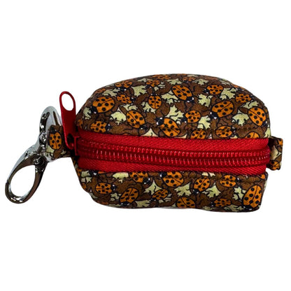Top view of a poo bag holder with ladybug pattern and red zipper.