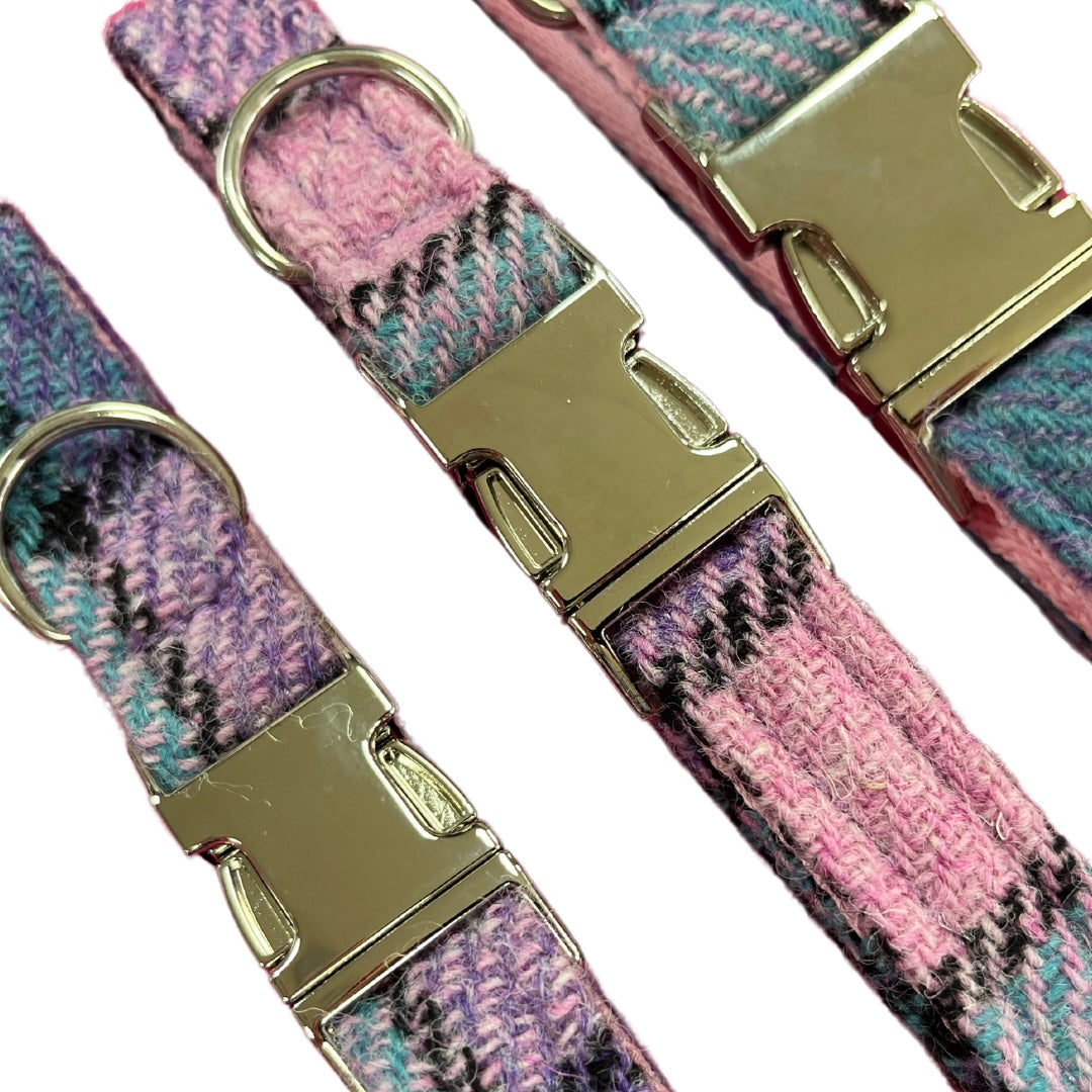 Harris Tweed dog collars in various sizes with metal clasps and a pink, lilac and black tartan pattern.