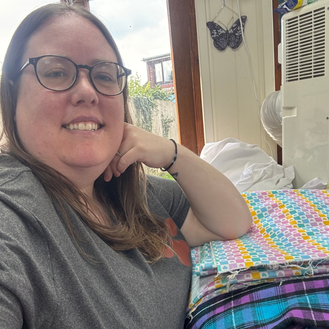 Nicole sitting next to a sewing machine with colourful fabric