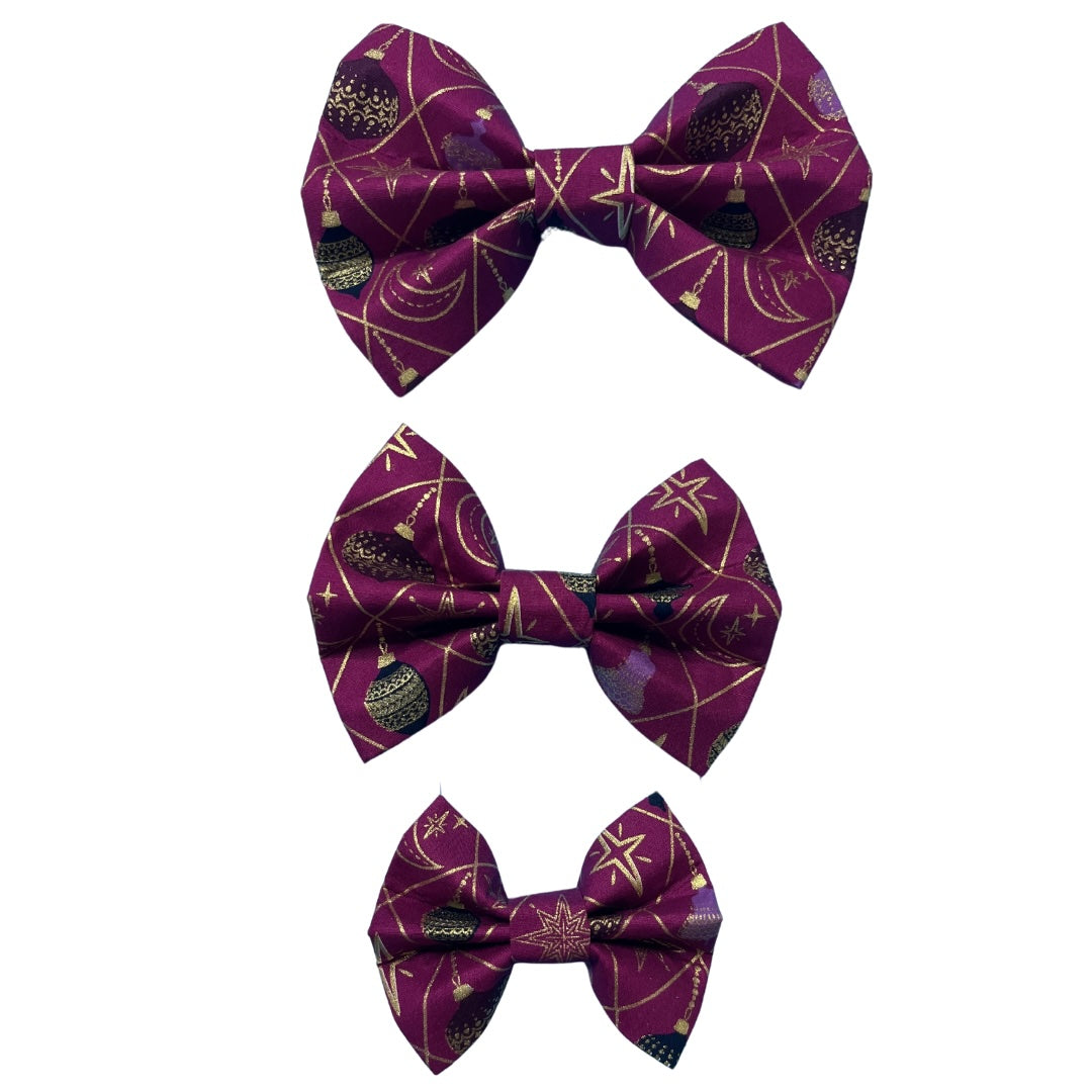 Three handmade festive bows in small, medium and large with baubles and gold detail on a rich purple background