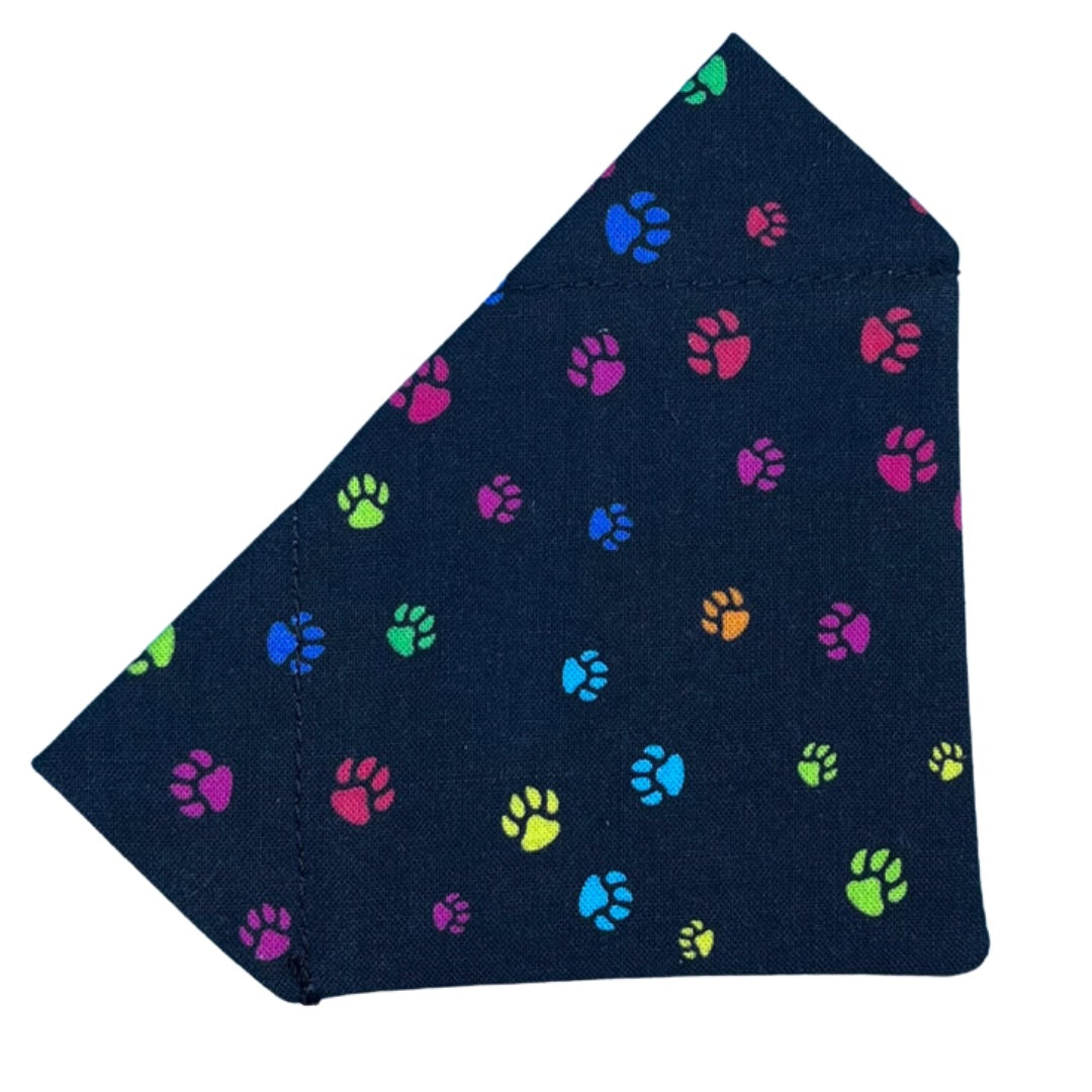 A black cotton bandana with colourful paw prints pattern, designed to slip on a collar.