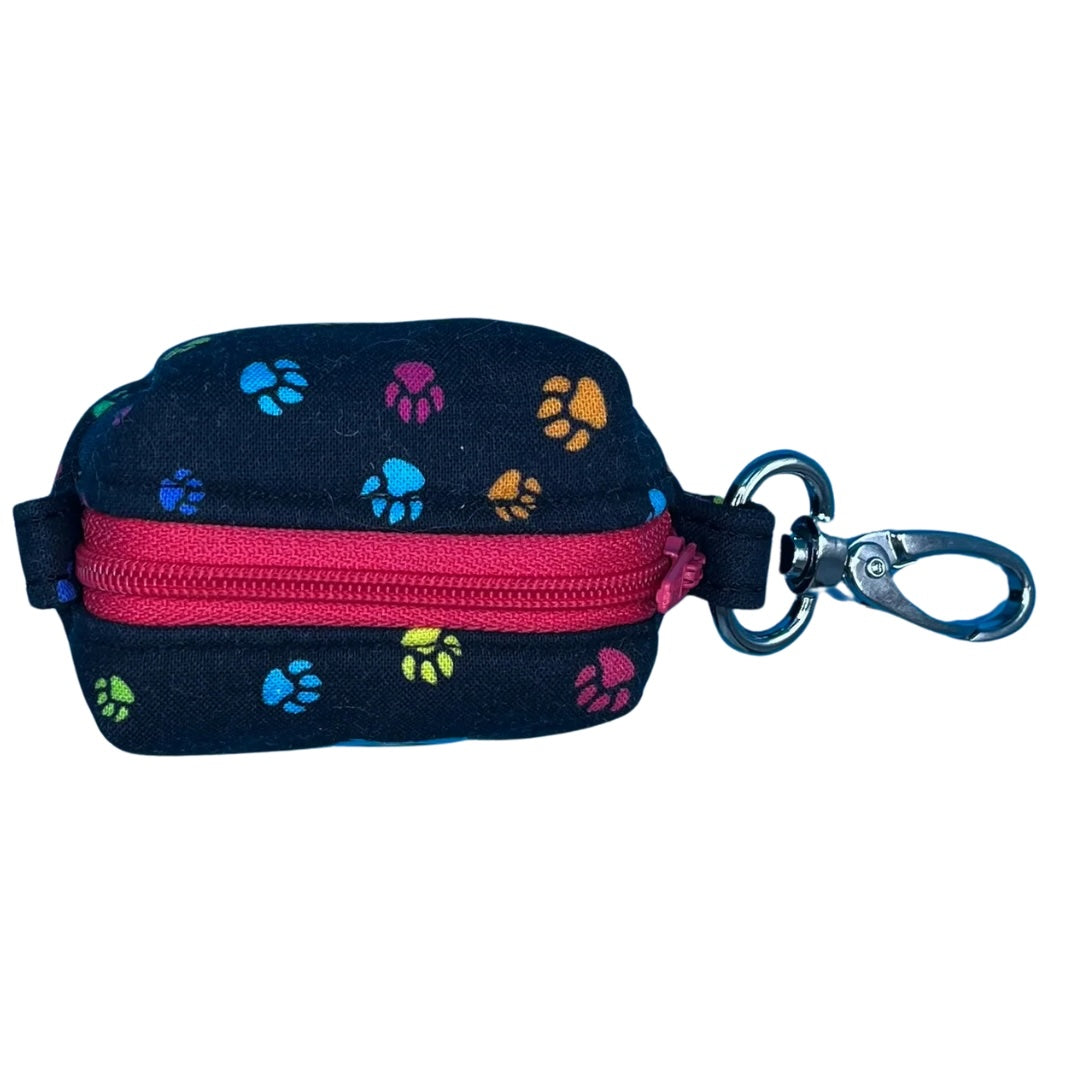 A top view of a fabric poo bag holder with a paw print pattern, multicoloured edges, and a pink zipper.