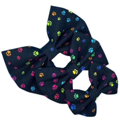 Three fabric dog bows with a paw print pattern on a black background