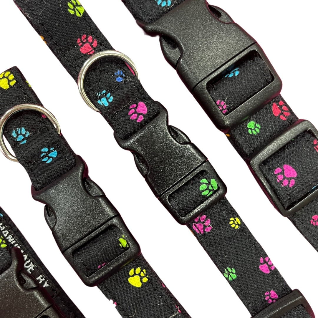 Adjustable dog collar with a paw print pattern, featuring a plastic buckle and  metal D-ring.