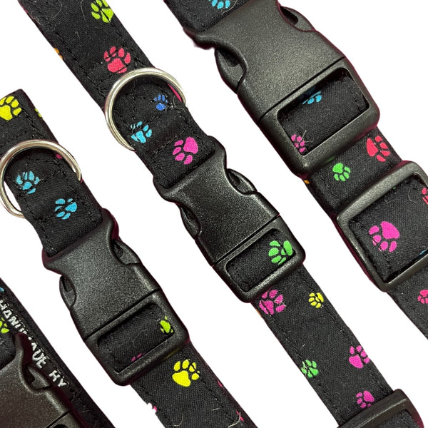 Adjustable dog collar with a paw print pattern, featuring a plastic buckle and  metal D-ring.