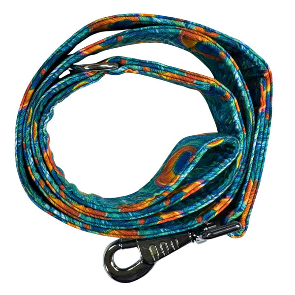 Top view of a blue, green and Orange peacock feather patterned dog lead with silver clip