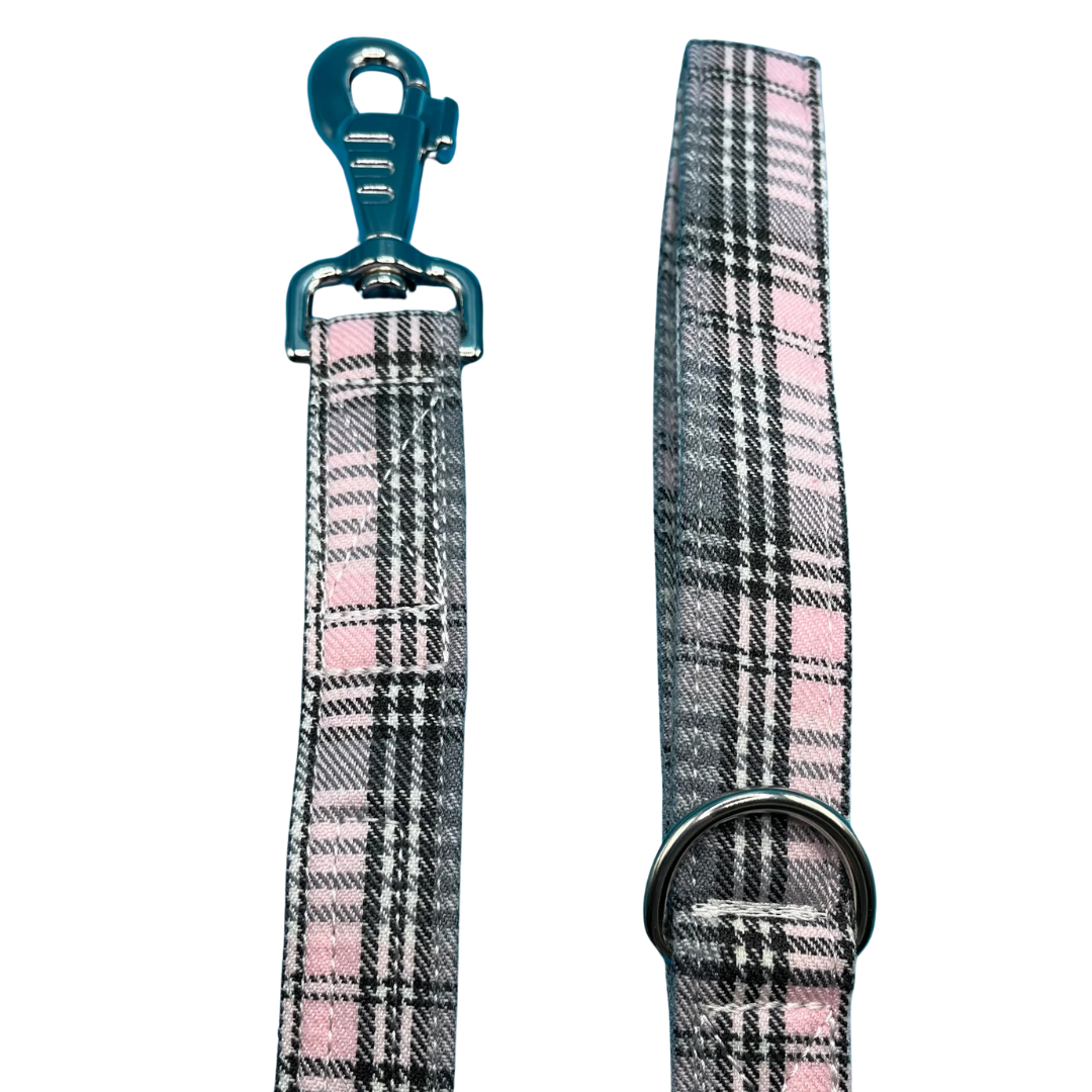 A pink and grey sugar tartan dog lead with silver metal hardware, Swivel clip for attaching to a dog's collar and a metal D ring for accessories.
