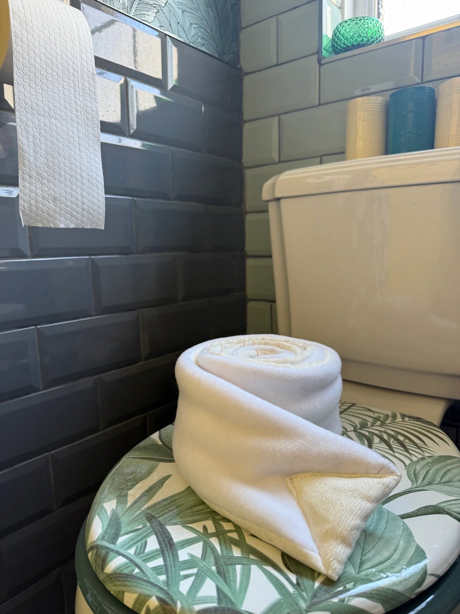 Poo-Dun-it dog enrichment toy draped over a toilet seat in a tiled bathroom