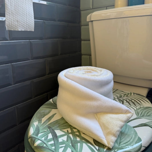 Poo-Dun-it dog enrichment toy draped over a toilet seat in a tiled bathroom close up