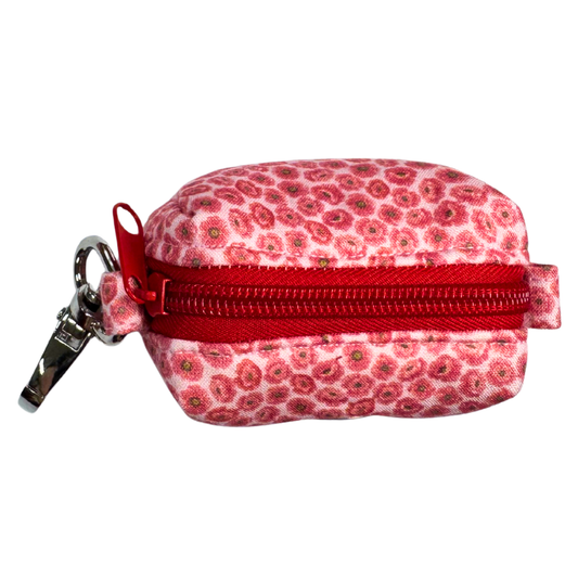 Top view of a small pink floral-patterned poo bag holder with a red zipper