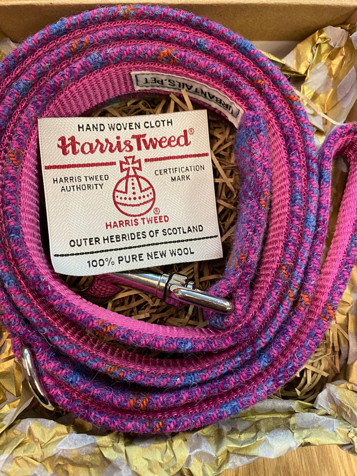 Pink and purple Harris Tweed fabric handmade dog lead with a label on a gold background