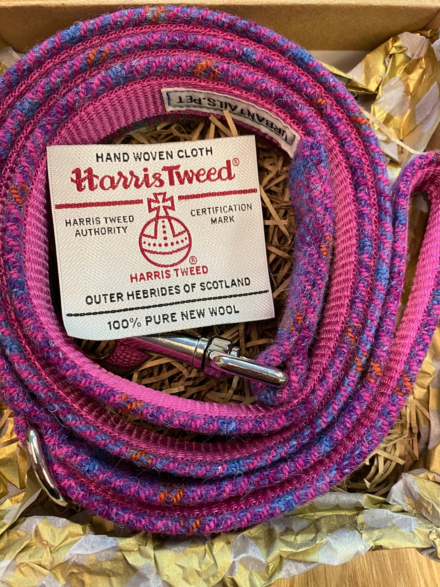 Pink and purple Harris Tweed fabric handmade dog lead with a label on a gold background