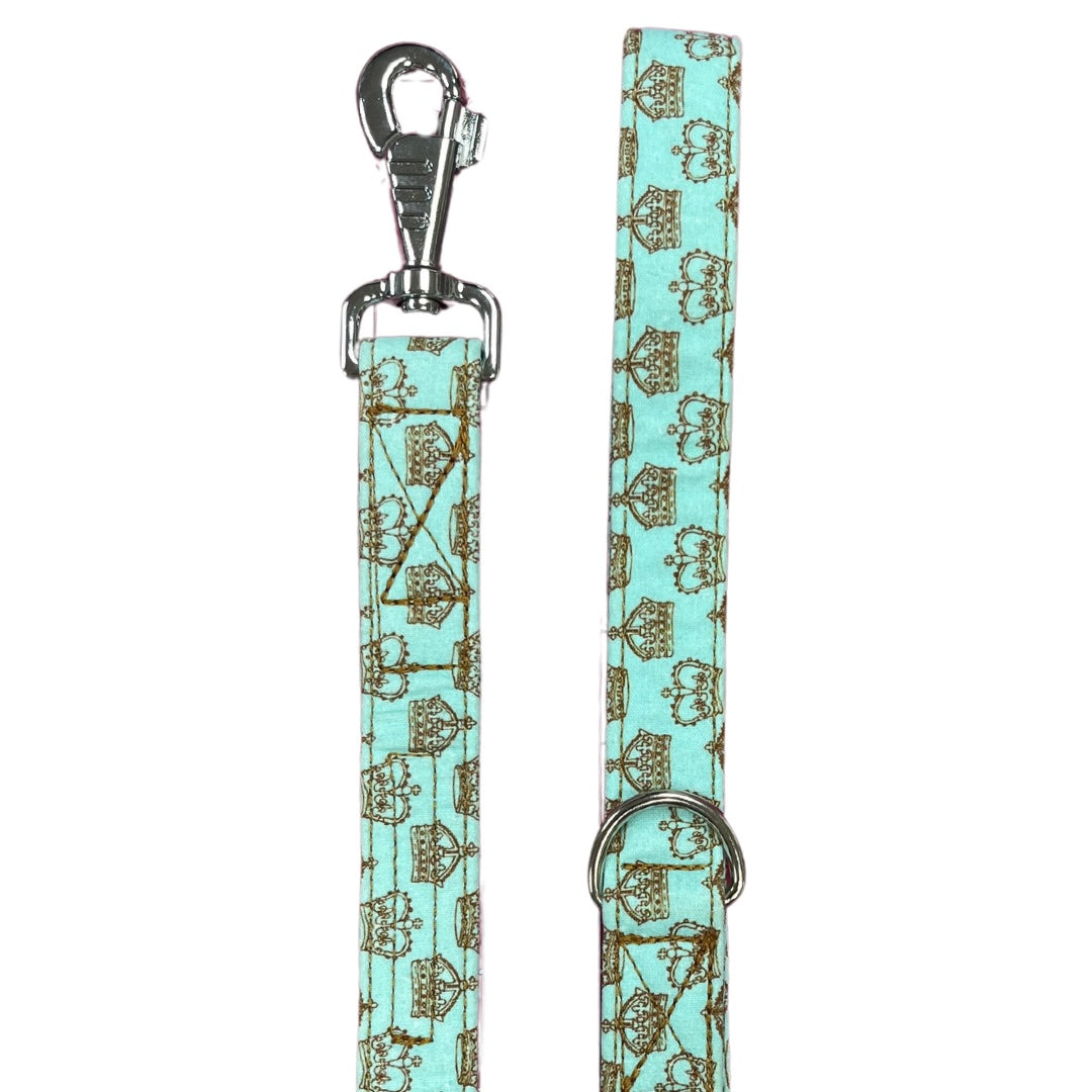 A blue fabric dog lead with a gold crown pattern and metal D Ring, finished with a heavy-duty swivel clip.