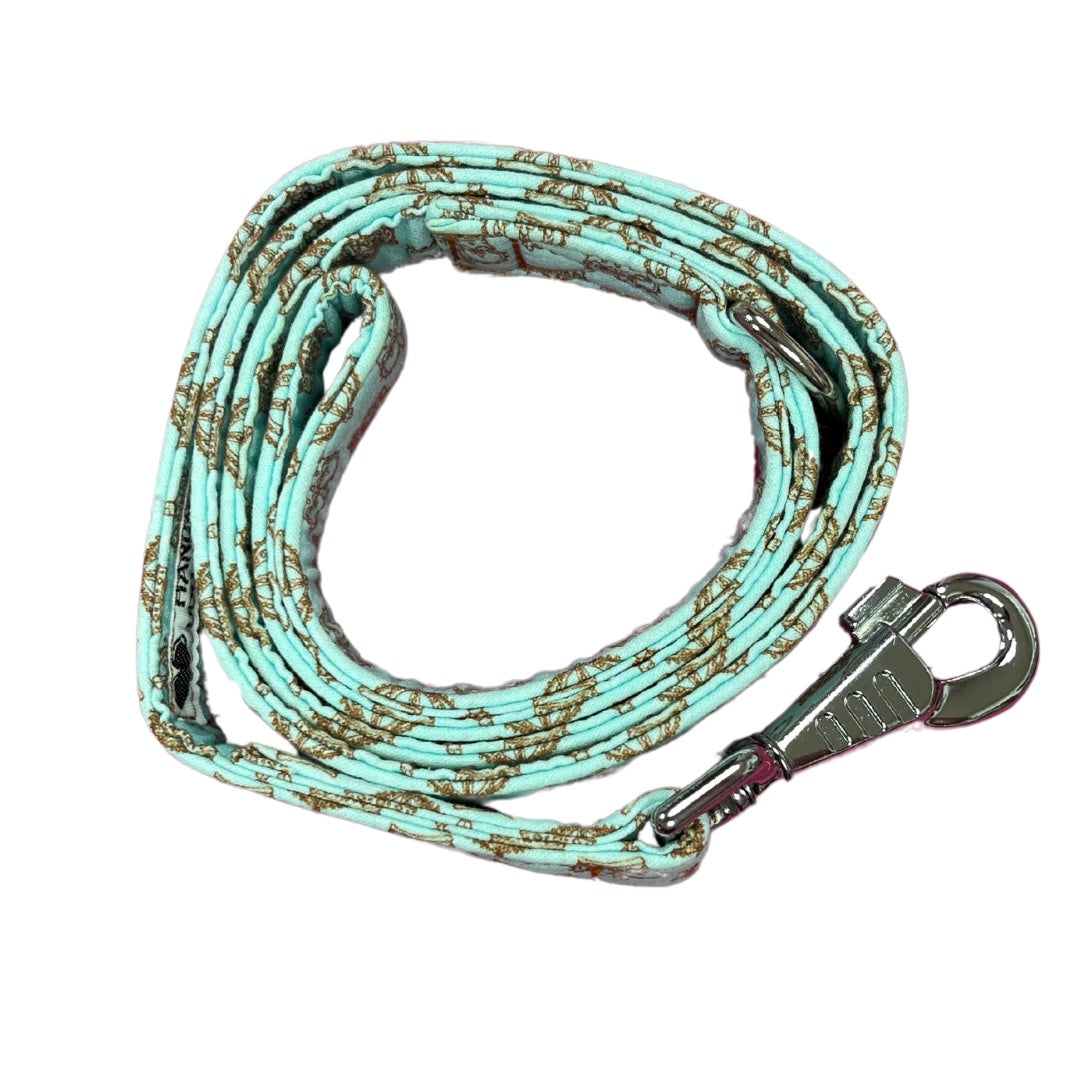 A coiled up blue fabric dog lead with a gold crown pattern and metal D Ring, finished with a heavy-duty swivel clip.
