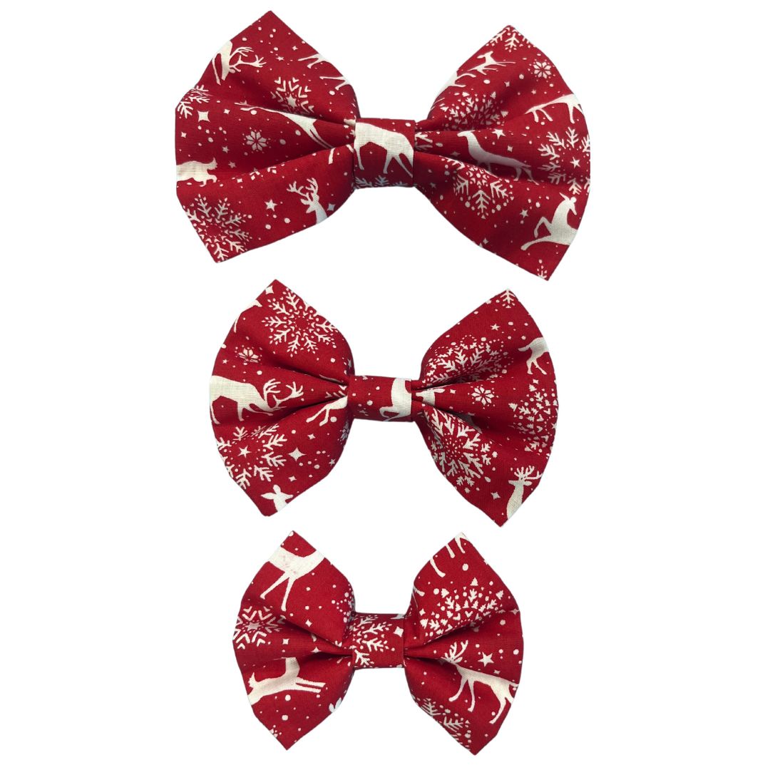 Three handmade red bow ties in small, medium and large with a snowflakes and reindeer pattern.