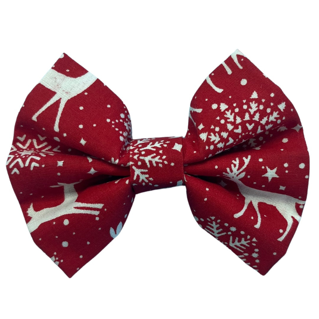 A red dog bow tie with a snowflakes and reindeer pattern.