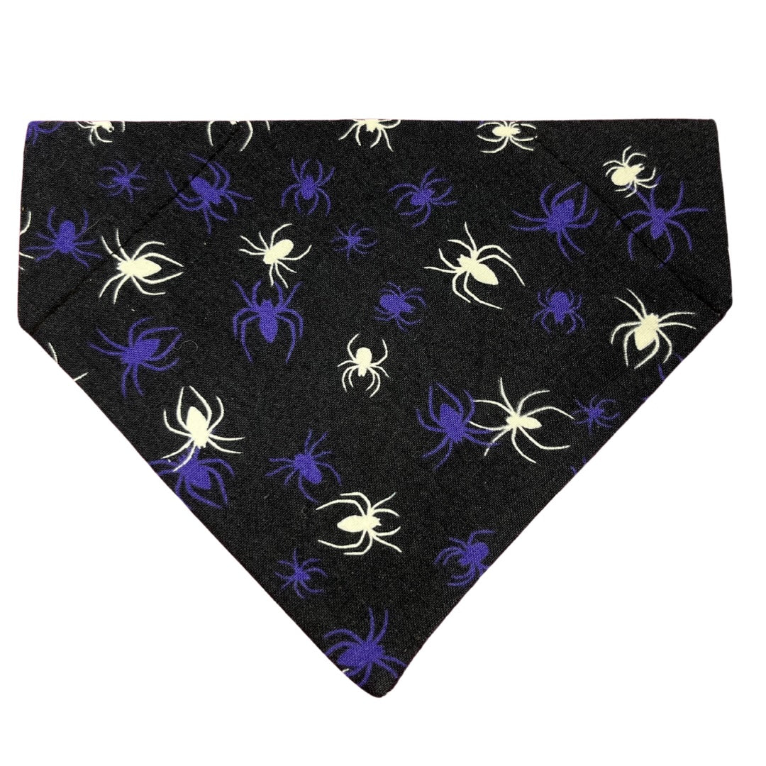 A Halloween glow in the dark spider dog bandana on a dark blue/black background