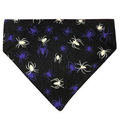 A Halloween glow in the dark spider dog bandana on a dark blue/black background
