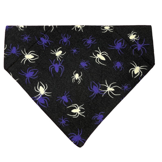A Halloween glow in the dark spider dog bandana on a dark blue/black background