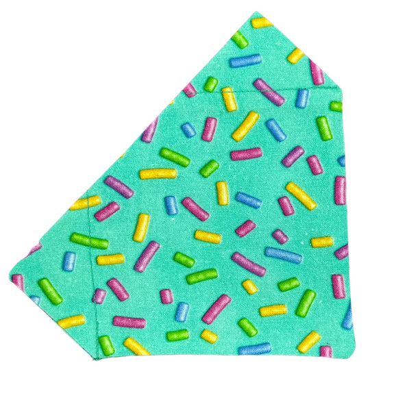 A green dog bandana with a pattern of colourful sprinkles.