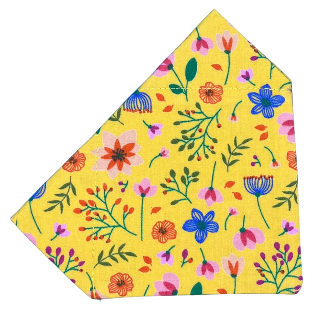 A yellow bandana with a floral pattern, including various flowers in blue and pink, designed for dogs.