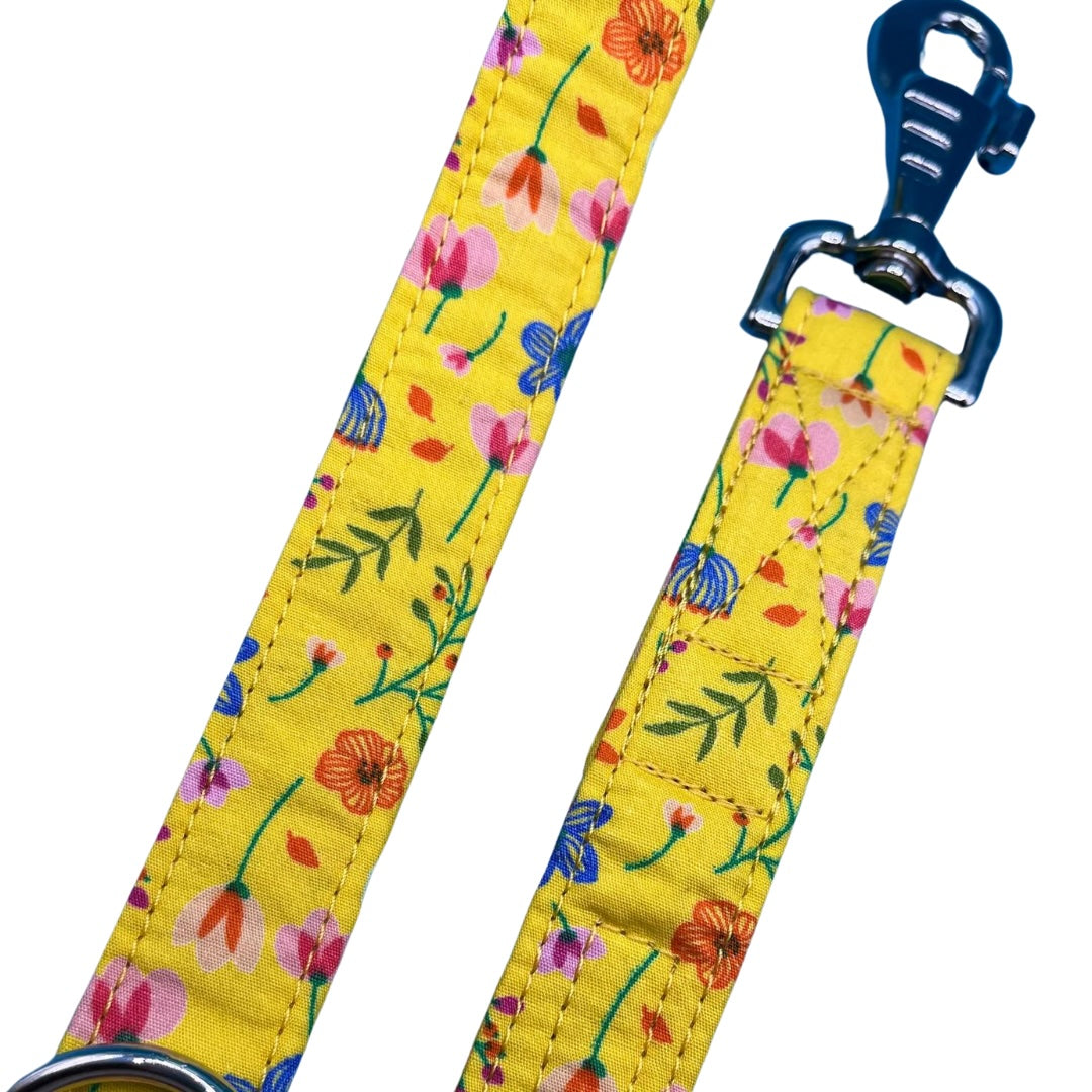 A close up of a yellow dog lead with a floral pattern, including a metal swivel clip and D ring.