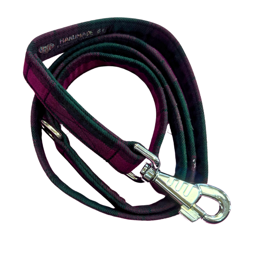 Top view of a plum and green Tartan Dog leash, coiled up to show the metal clip.