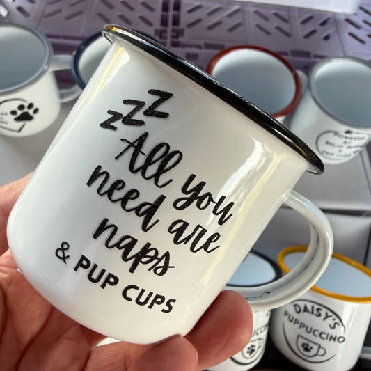 White mug with black text held by a hand, with more mugs in the background.