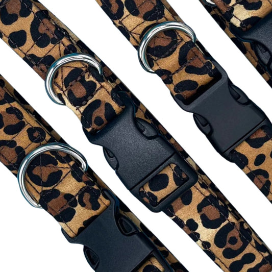A close up of adjustable brown and black animal print dog collars with metal D rings and plastic buckles.