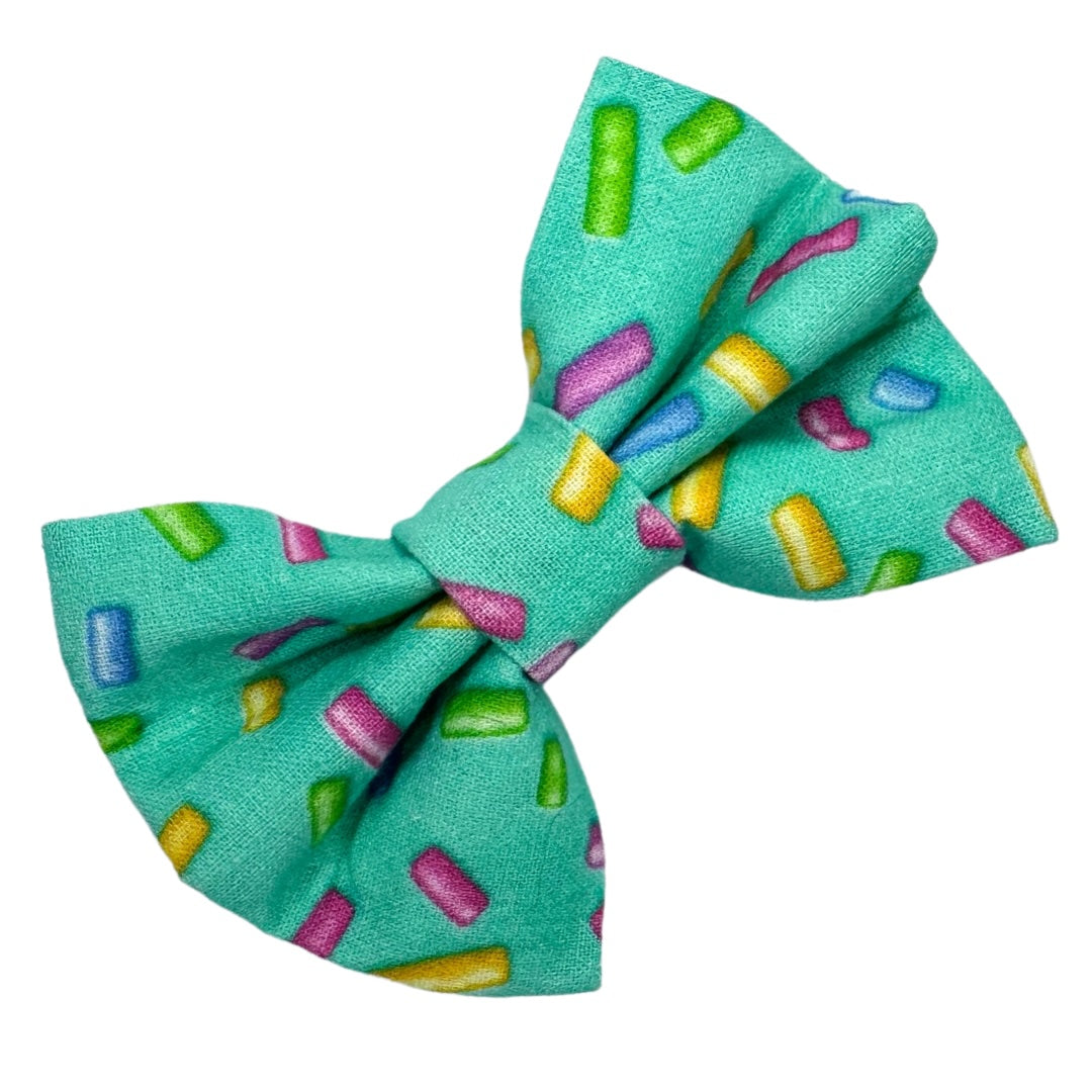 A green dog bow tie with a multi-coloured sprinkle pattern on it.